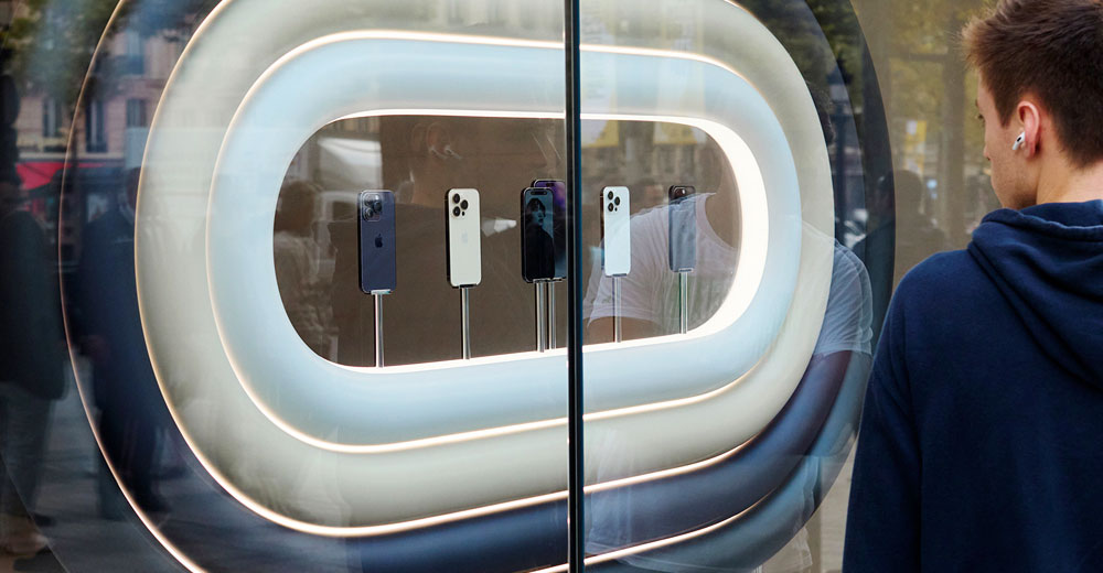 A young man looking at the iPhone 14 window display in Paris