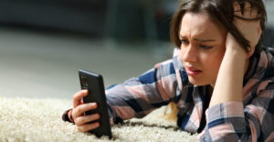 a worried teenager looking at her smartphone
