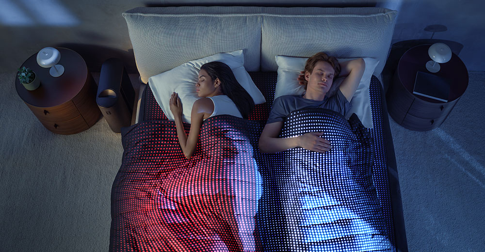 Couple sleeping under a dual-zone heated and cooled blanket, demonstrating personalized temperature zones in the Eight Sleep Pod 5 system.